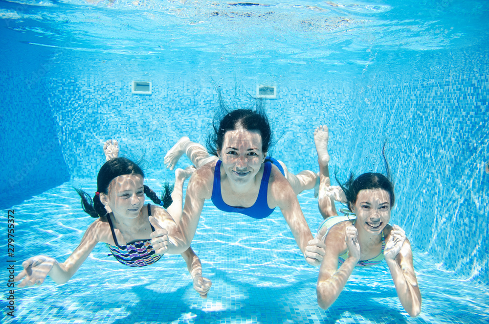 Family swims in pool underwater, happy active mother and children have fun under water, fitness and sport with kids on summer vacation on resort