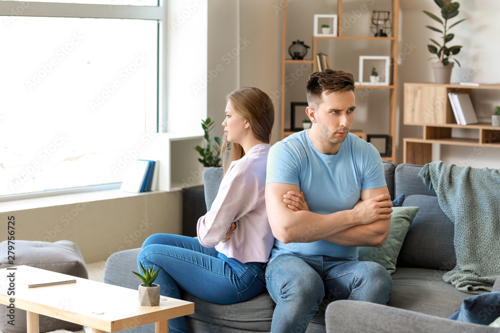 Young offended couple after quarrel sitting on sofa at home Young offended couple after quarrel sitting on sofa at home
