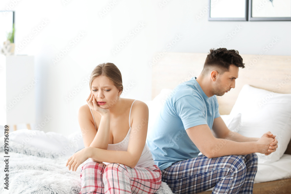 Sad young couple after quarrel sitting on bed Sad young couple after quarrel sitting on bed