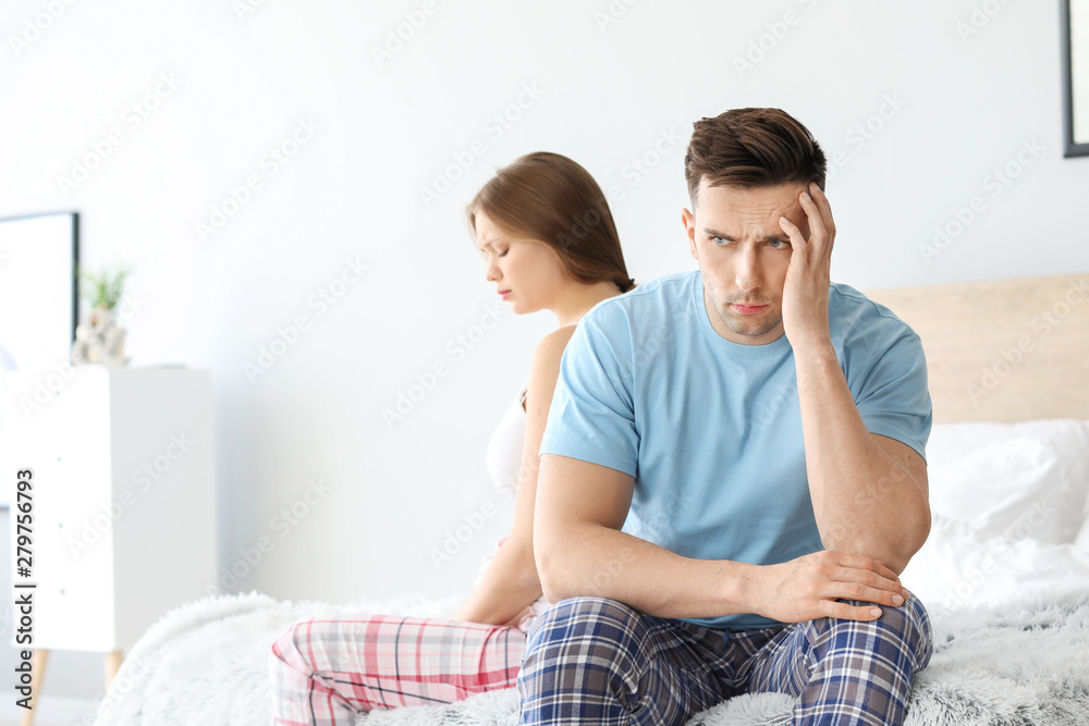 Upset young couple after quarrel sitting on bed Upset young couple after quarrel sitting on bed