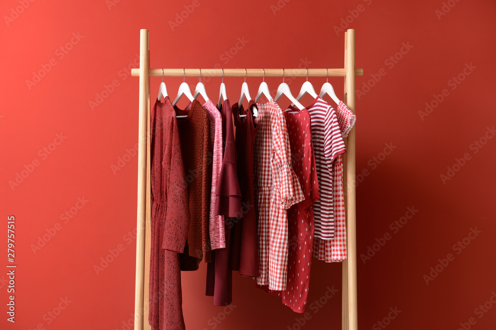Rack with hanging clothes on color background - obrazy, fototapety, plakaty 