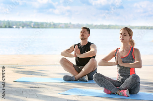 Sporty couple in love meditating outdoors