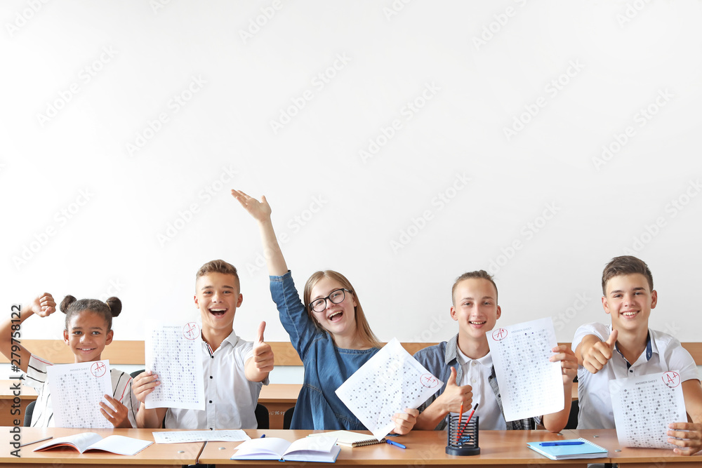 Happy classmates with results of school test in classroom - obrazy, fototapety, plakaty 