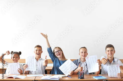 Happy classmates with results of school test in classroom
