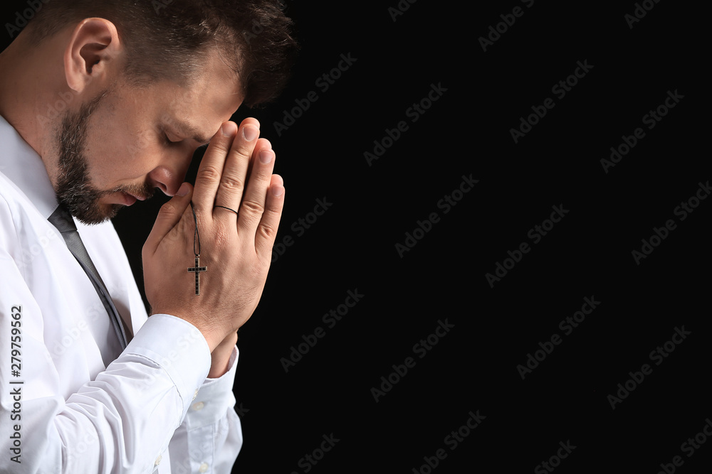 Religious man praying on dark background Religious man praying on dark background