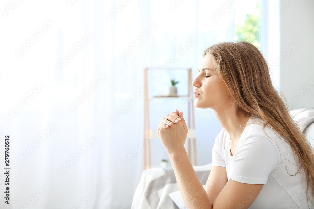 Religious young woman praying to God at home Religious young woman praying to God at home