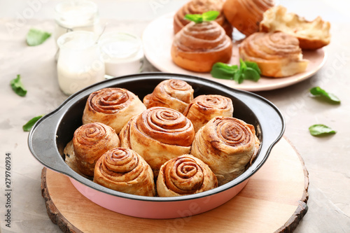Baking tray with tasty cinnamon buns on table