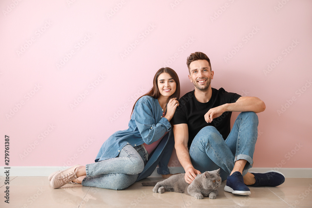 Happy couple with cute cat near color wall Happy couple with cute cat near color wall
