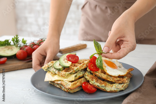 Woman decorating tasty squash waffles on plate, closeup