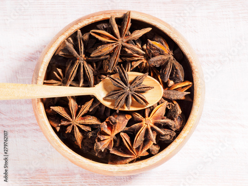 Anise (Anisum vulgare) on a wooden cup on a wooden background with spoon