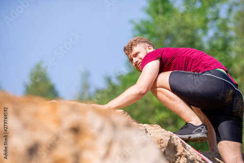 Runner climbing on rocks obstacles in the extreme cross-country race © leszekglasner