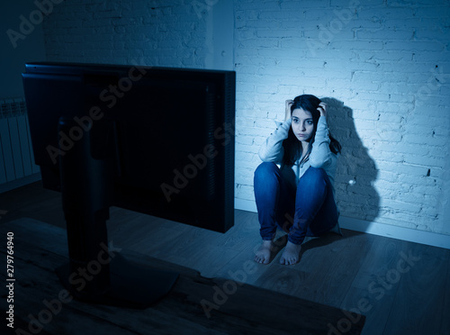 Scared and sad woman on the floor staring at computer in fear suffering cyberbullying