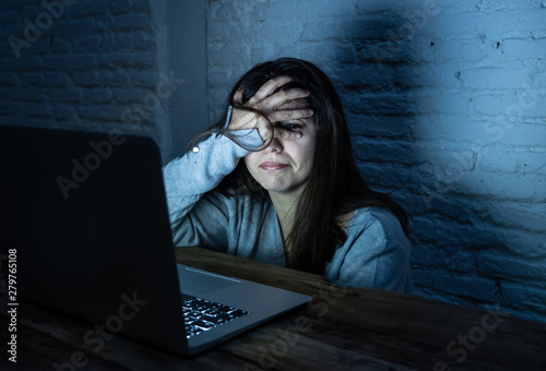 Foto Scared woman on laptop in the dark feeling fear suffering online harassment and