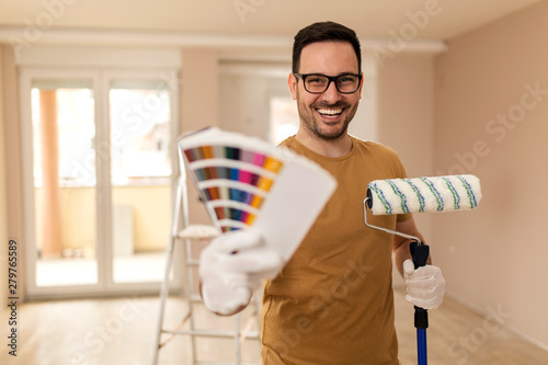 Young man painting apartment.