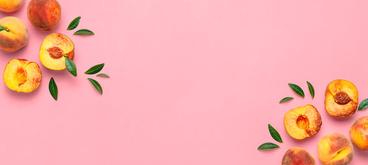Flat lay composition with peaches. Ripe juicy peaches with green leaves on pink background. Flat lay, top view, copy space. Fresh organic fruit, vegan food. Harvest concept.
