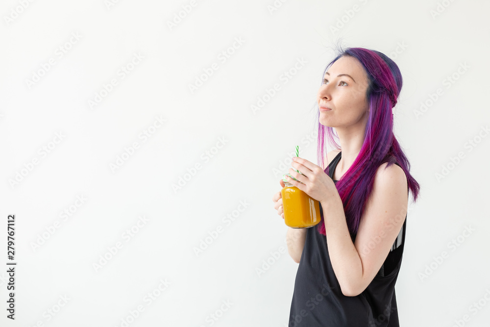 Cute young mixed race hipster girl with colored hair drinks fruit smoothie before starting a yoga class on a white background with copy space. Healthy lifestyle concept. Copyspase. Cute young mixed race hipster girl with colored hair drinks fruit smoothie before starting a yoga class on a white background with copy space. Healthy lifestyle concept. Copyspase.