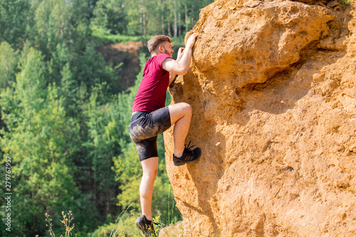 Fit man climbing on rocks obstacles in the boot camp