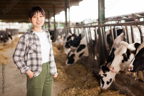 Chinese female farmer posing in cowshed at dairy farm
