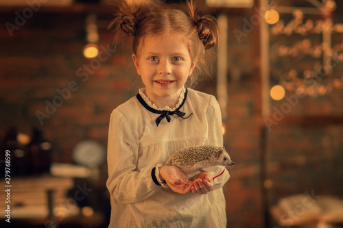 girl holding hedgehog in the hands with blurred background