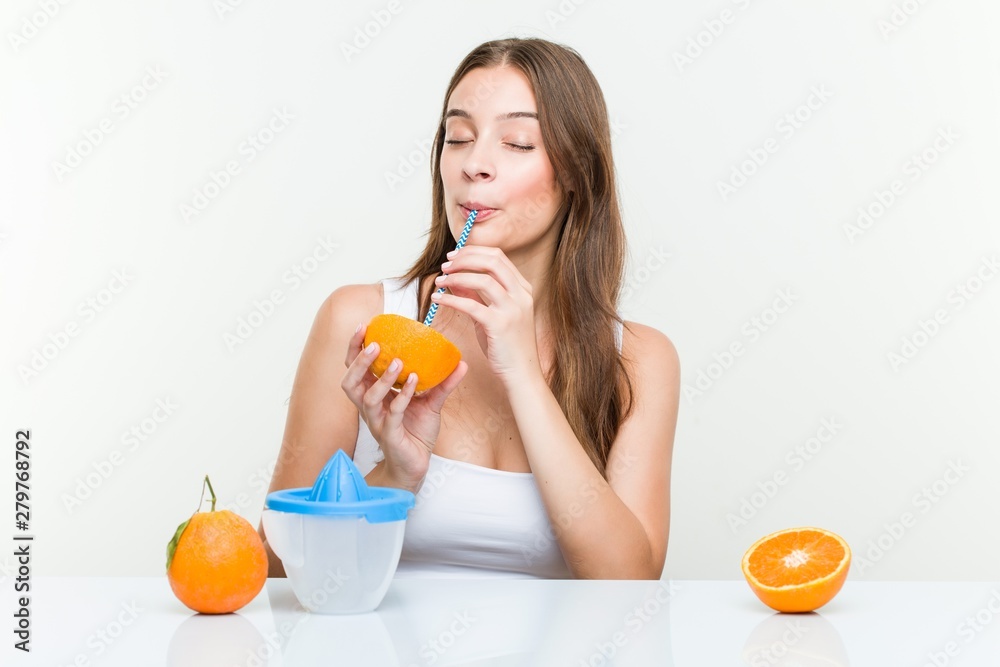 Young caucasian woman drinking an orange with a straw. Healthy life concept Young caucasian woman drinking an orange with a straw. Healthy life concept