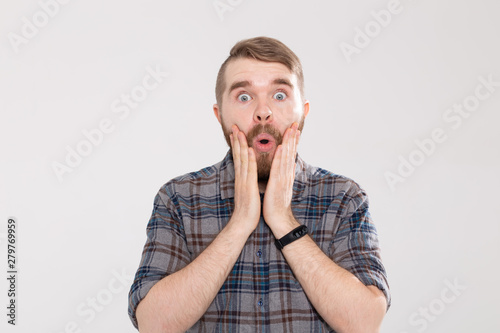 Stylish young hipster man with a mustache and beard joyfully opens his mouth on a white background. Concept of surprise and shock.