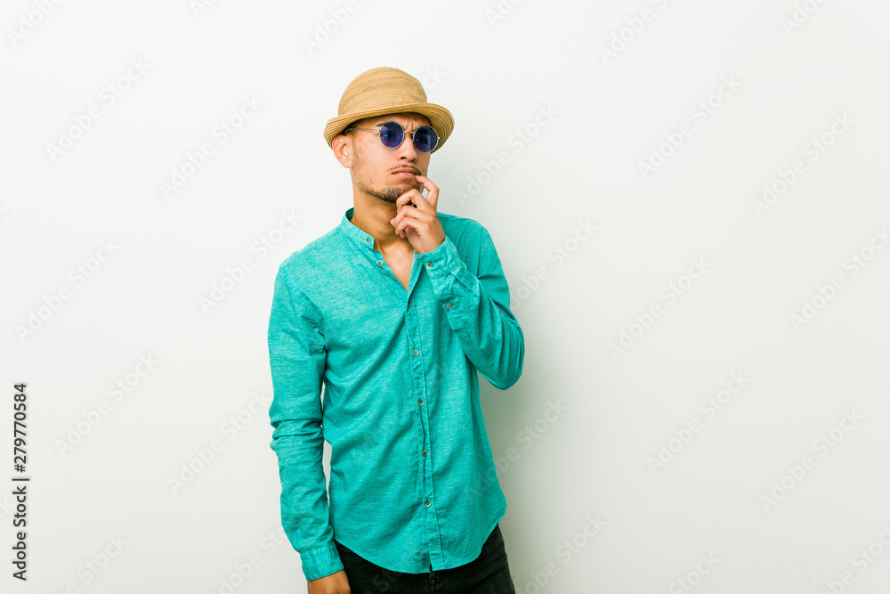 Young hispanic man wearing a summer clothes looking sideways with doubtful and skeptical expression. Young hispanic man wearing a summer clothes looking sideways with doubtful and skeptical expression.