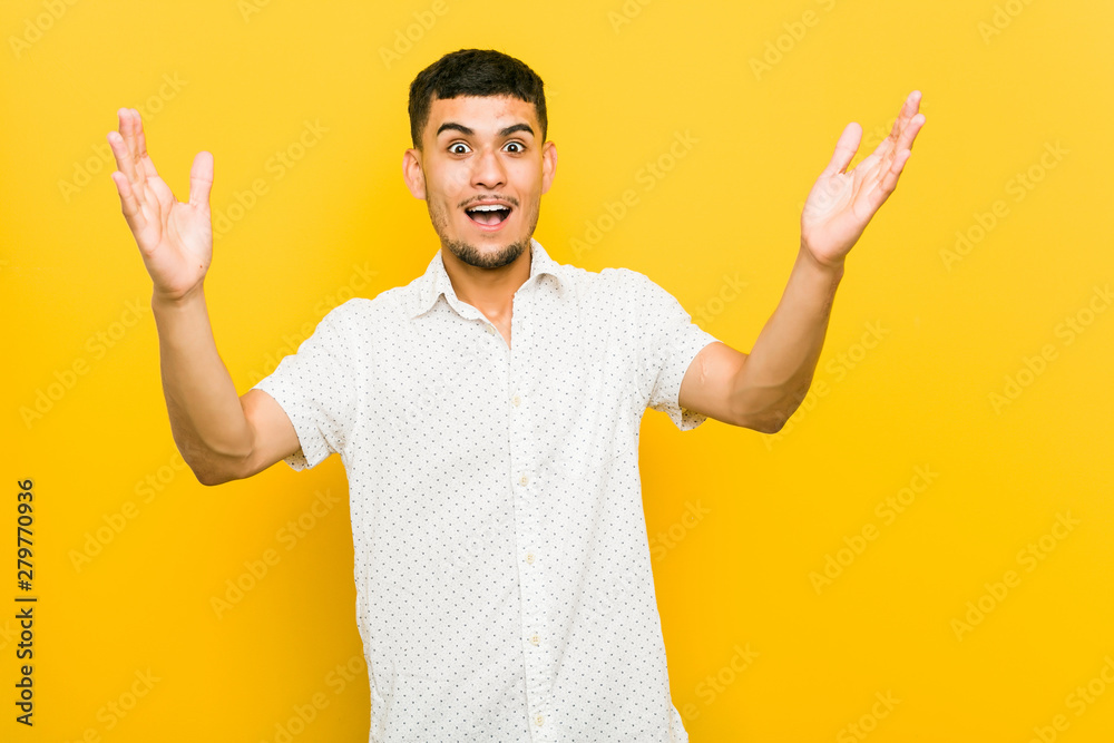 Young hispanic man receiving a pleasant surprise, excited and raising hands. Young hispanic man receiving a pleasant surprise, excited and raising hands.