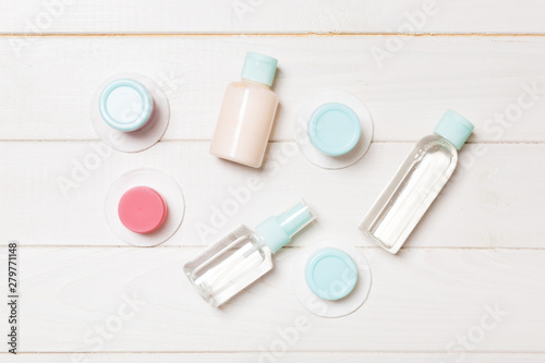 Set of travel size cosmetic bottles on white wooden background. Flat lay of cream jars. Top view of bodycare style concept
