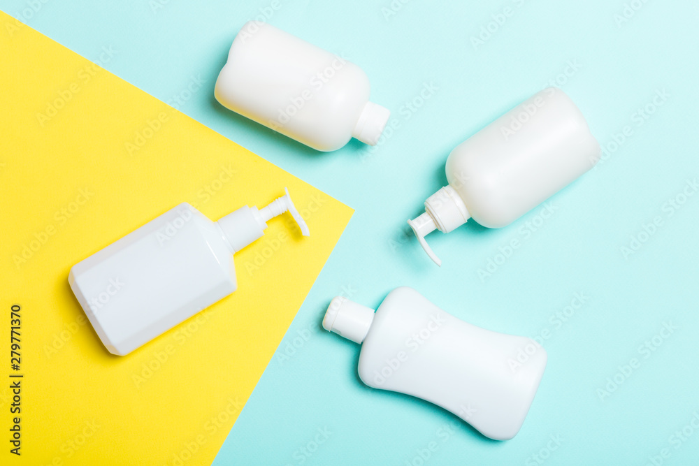 Set of White Cosmetic containers isolated on yellow and blue background, top view with copy space. Group of plastic bodycare bottle containers with empty space for you design