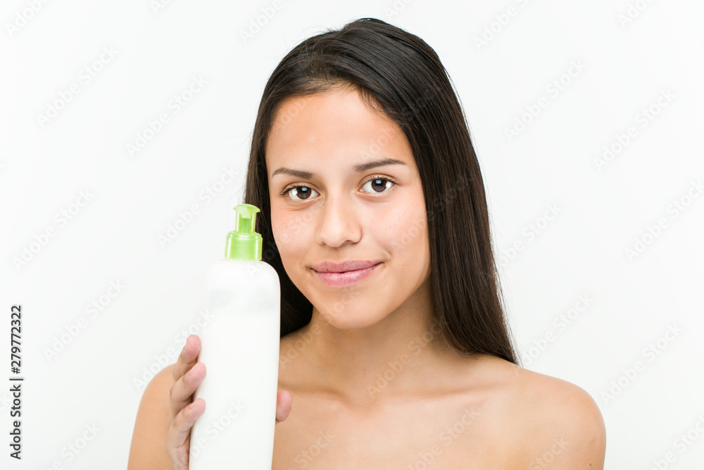 Close up of a beautiful and natural hispanic young woman holding a moisturizing cream bottle Close up of a beautiful and natural hispanic young woman holding a moisturizing cream bottle