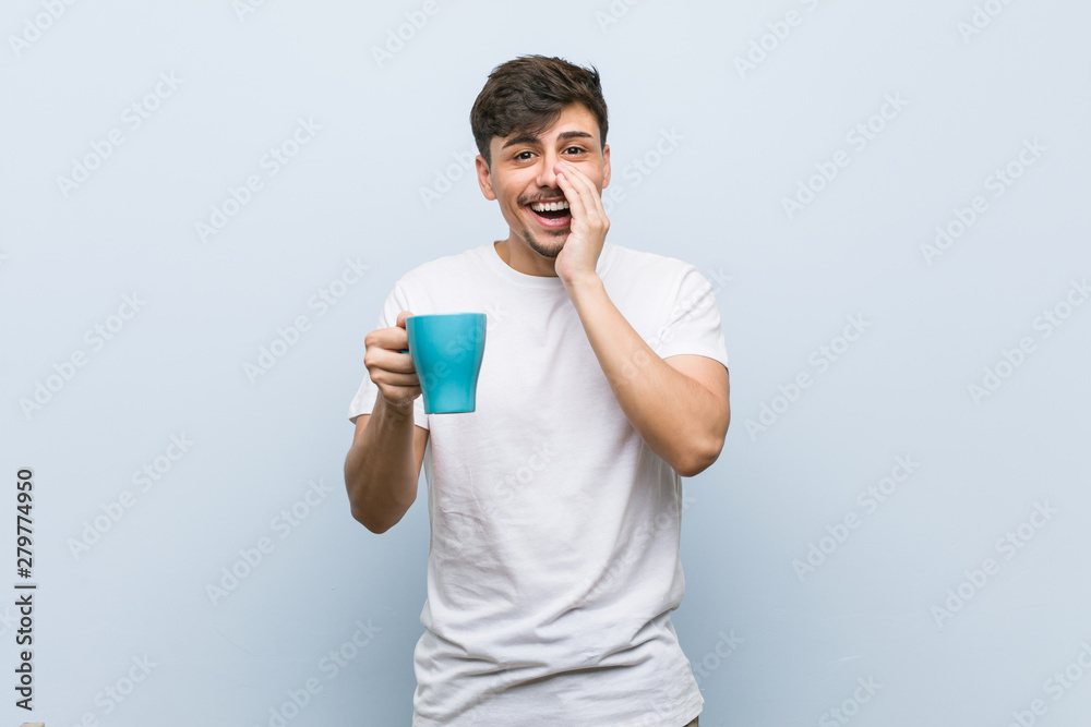 Young hispanic man holding a cup shouting excited to front. Young hispanic man holding a cup shouting excited to front.