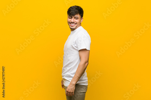 Young hispanic casual man looks aside smiling, cheerful and pleasant.