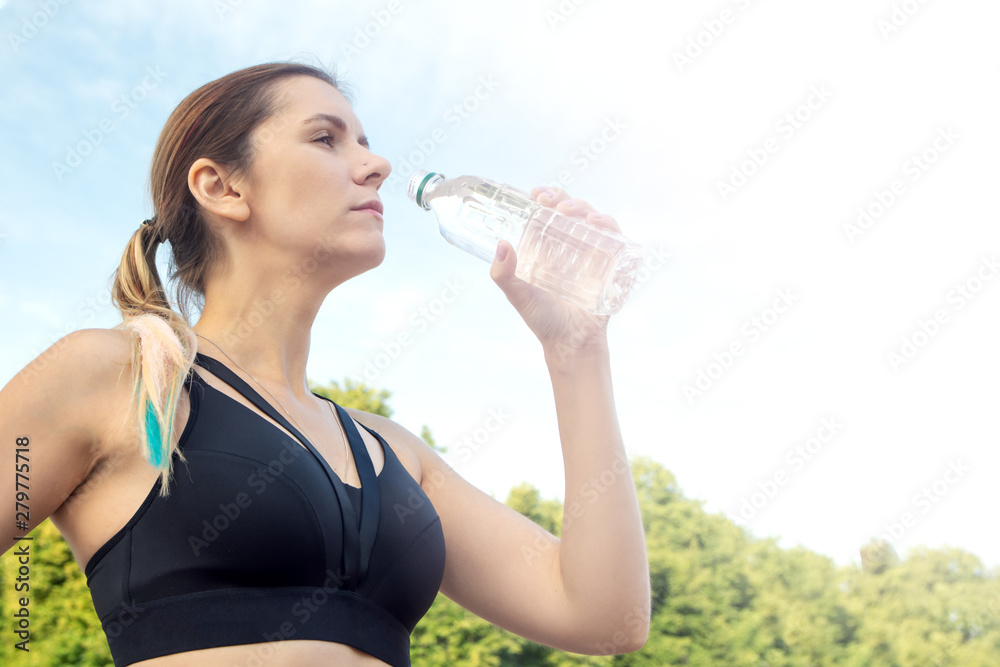 Portrait of young beautiful dark-haired fitness woman drinking water at summer green park. Portrait of young beautiful dark-haired fitness woman drinking water at summer green park.