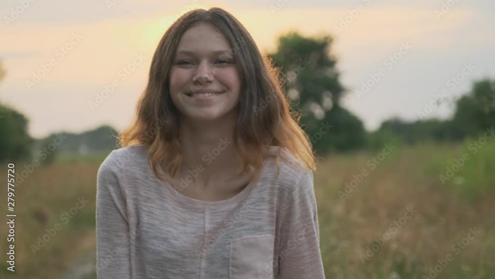 Portrait of beautiful cheerful smiling laughing teenager girl 15 years old, with brown flying hair looking at camera, nature sunset background Portrait of beautiful cheerful smiling laughing teenager girl 15 years old, with brown flying hair looking at camera, nature sunset background