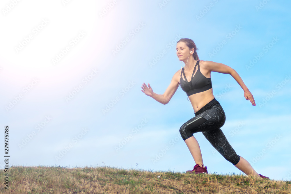 Side view beautiful woman running on the edge of the hill. background blue sky Side view beautiful woman running on the edge of the hill. background blue sky