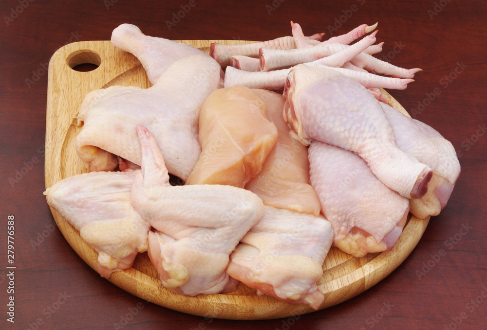 Assortment of raw chicken meaton round cutting board on table