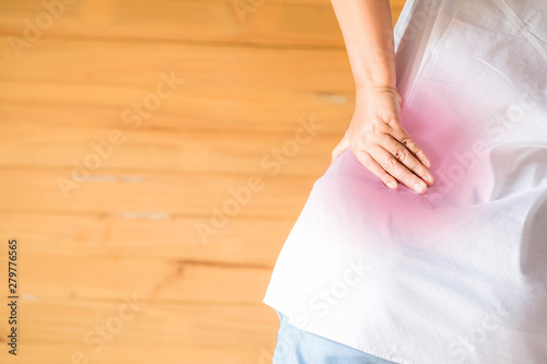 Female holding hand to spot of Abdomen. Concept photo with red spot indicating location of the pain.