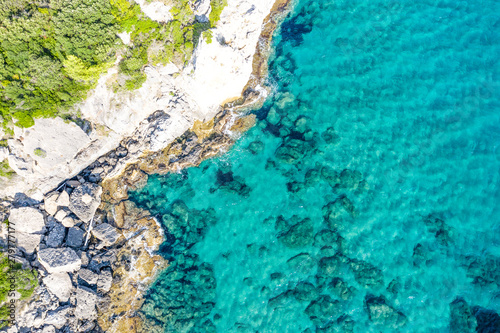 Aerial view of beautiful seashore in summer. Rocky beach and green islands seen from above.