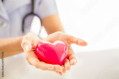 Female nurse with stethoscope holding heart
