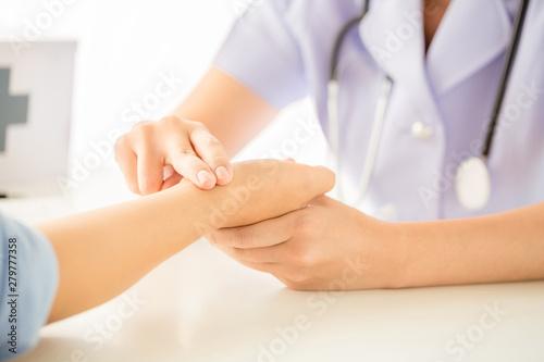 Doctor is checking patience's pulse by fingers
