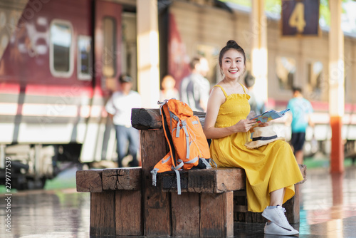 Foto Young Asia woman wanderer with trendy look searching direction on location map while traveling in train station