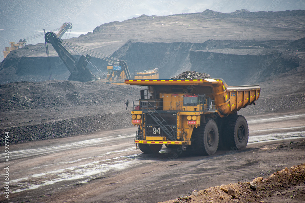 Big yellow mining truck hauling rock in dusty coal mine Big yellow mining truck hauling rock in dusty coal mine