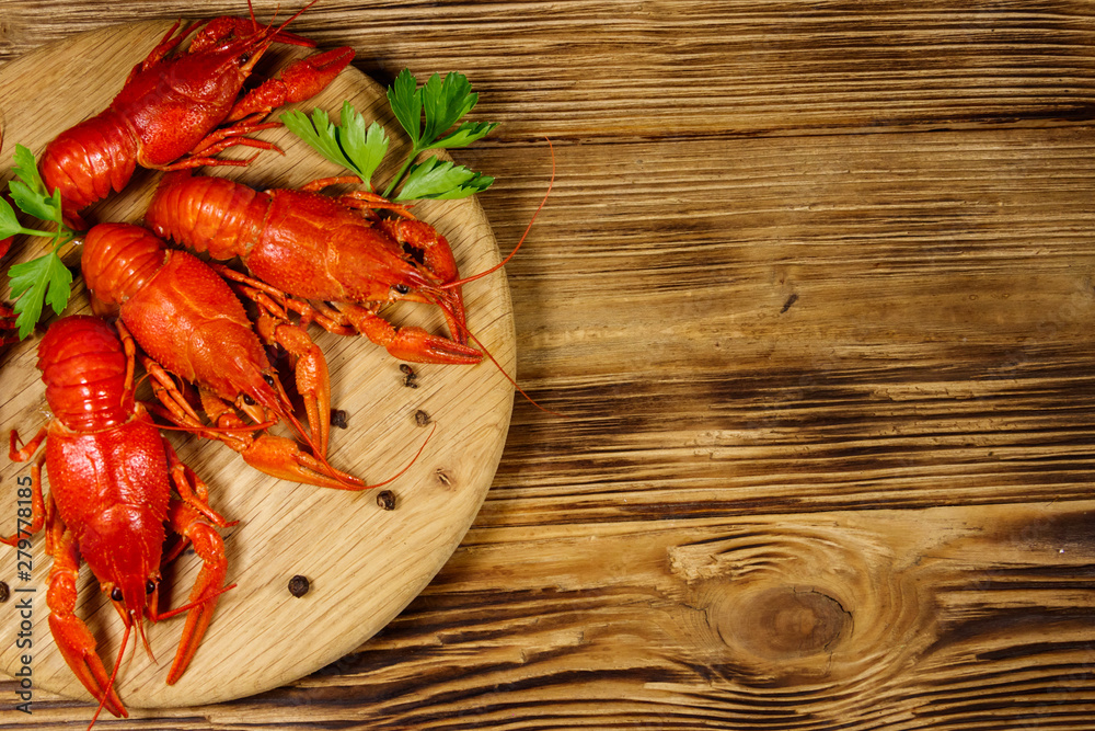 Boiled crayfish on cutting board on wooden table. Top view Boiled crayfish on cutting board on wooden table. Top view