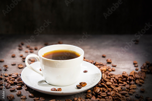 The cup of hot coffee with coffee beans