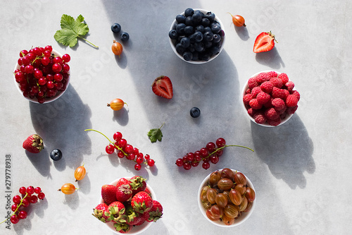 Assorted fresh ripe berries on a gray background. Strawberries, raspberries, gooseberries, blueberries and red currants. Organic Food. Top view.