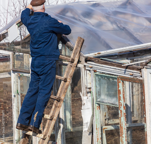 A man in the country repairing a greenhouse © schankz