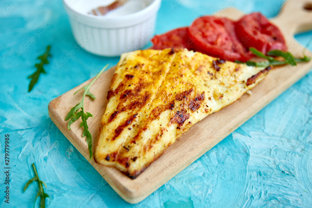 Grilled pike fillet with tomatoes on wooden board Grilled pike fillet with tomatoes on wooden board