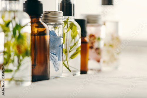 Transparent Bottles of essential oil with fresh herbs.