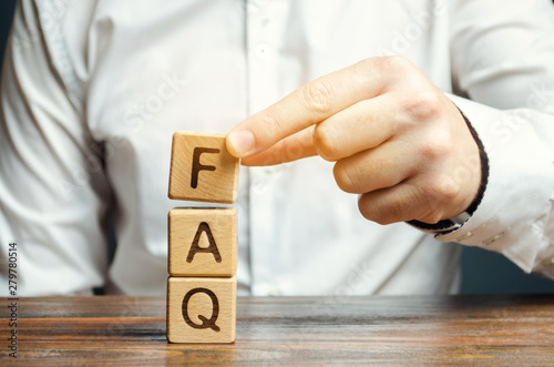 Businessman puts wooden blocks with the word FAQ (frequently asked questions). Collection of frequently asked questions on any topic and answers to them. Instructions and rules on Internet sites