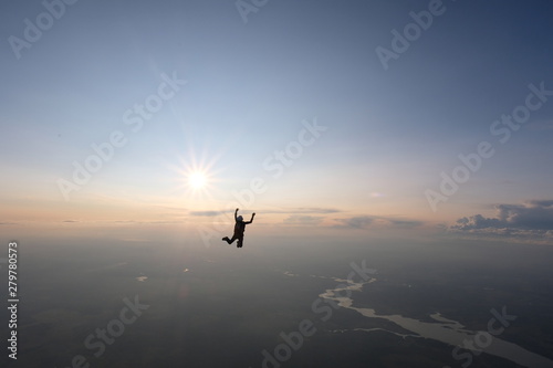 Skydiving. Sunset jump. A skydiver is falling near the sun.
